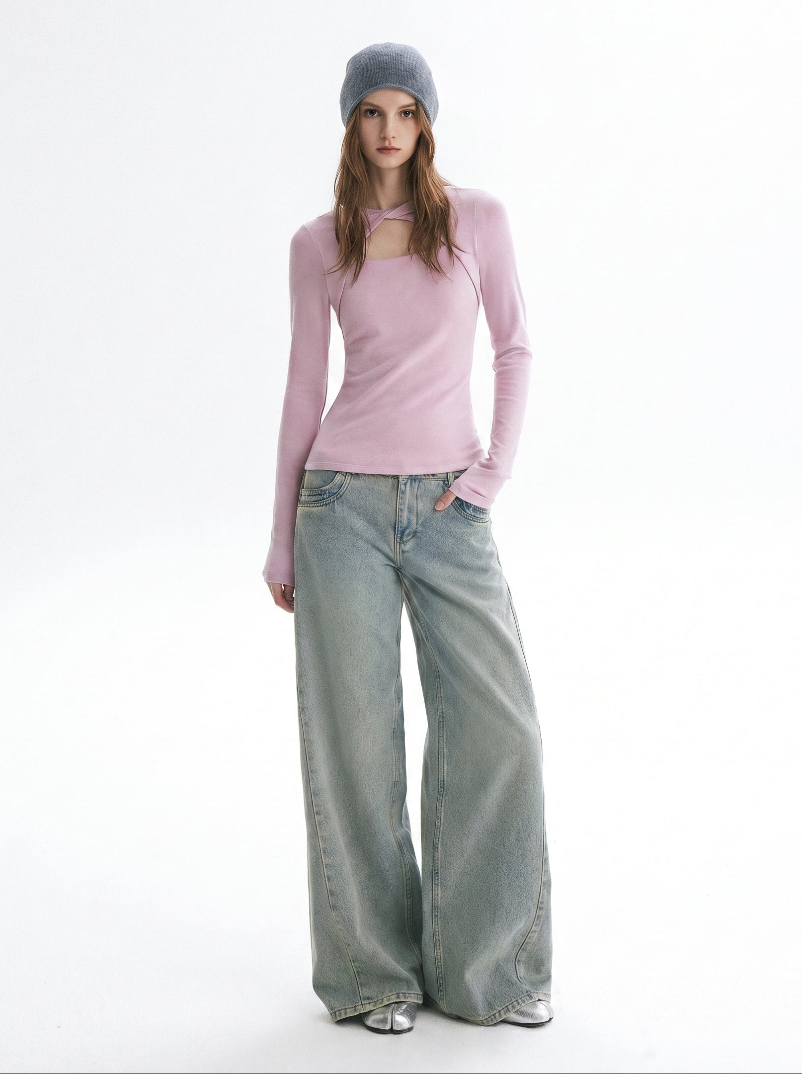Model wearing a pink asymmetric cutout long sleeve top with light wash wide leg jeans