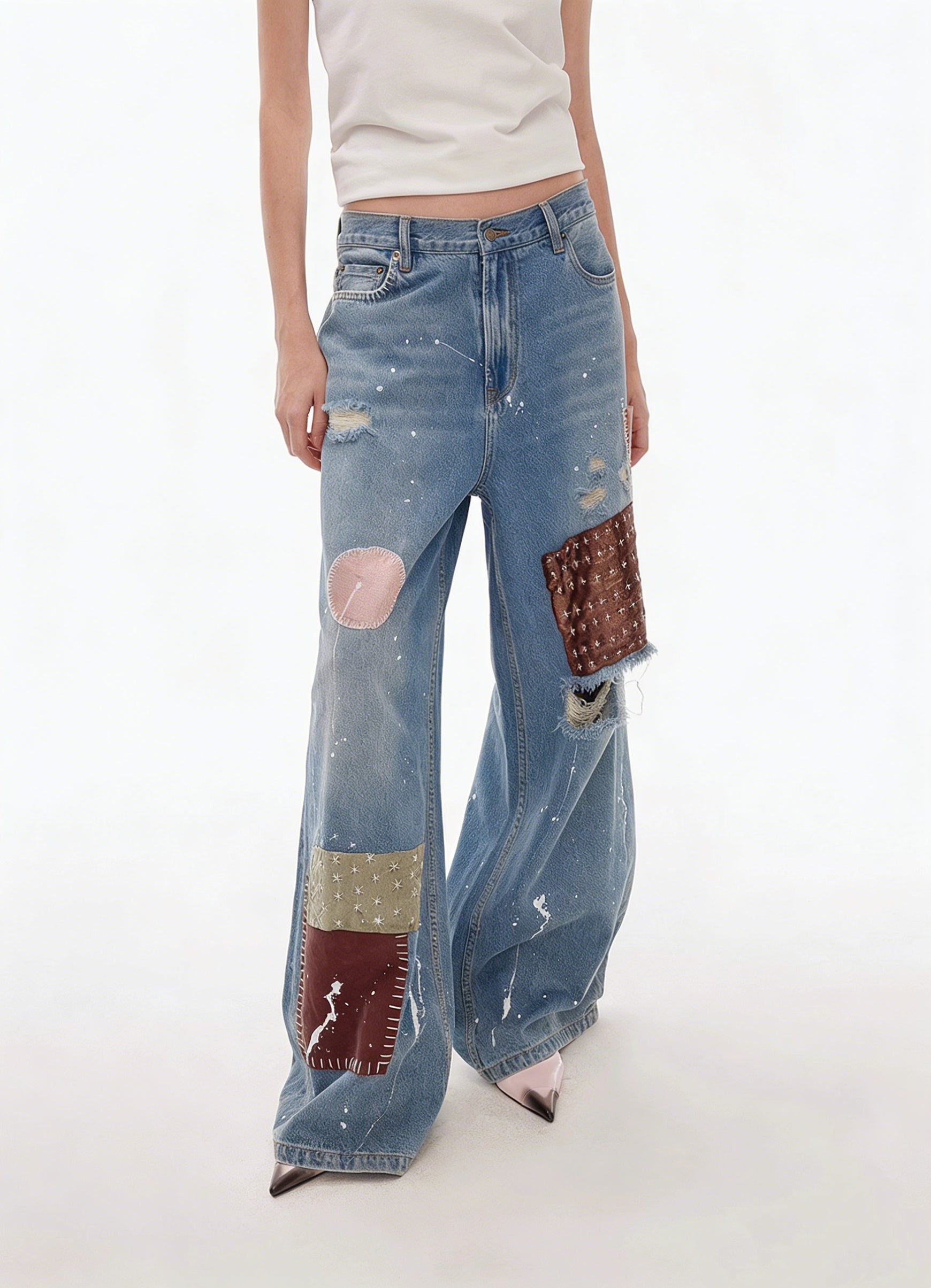 Three-quarter close-up of blue patchwork distressed wide-leg jeans