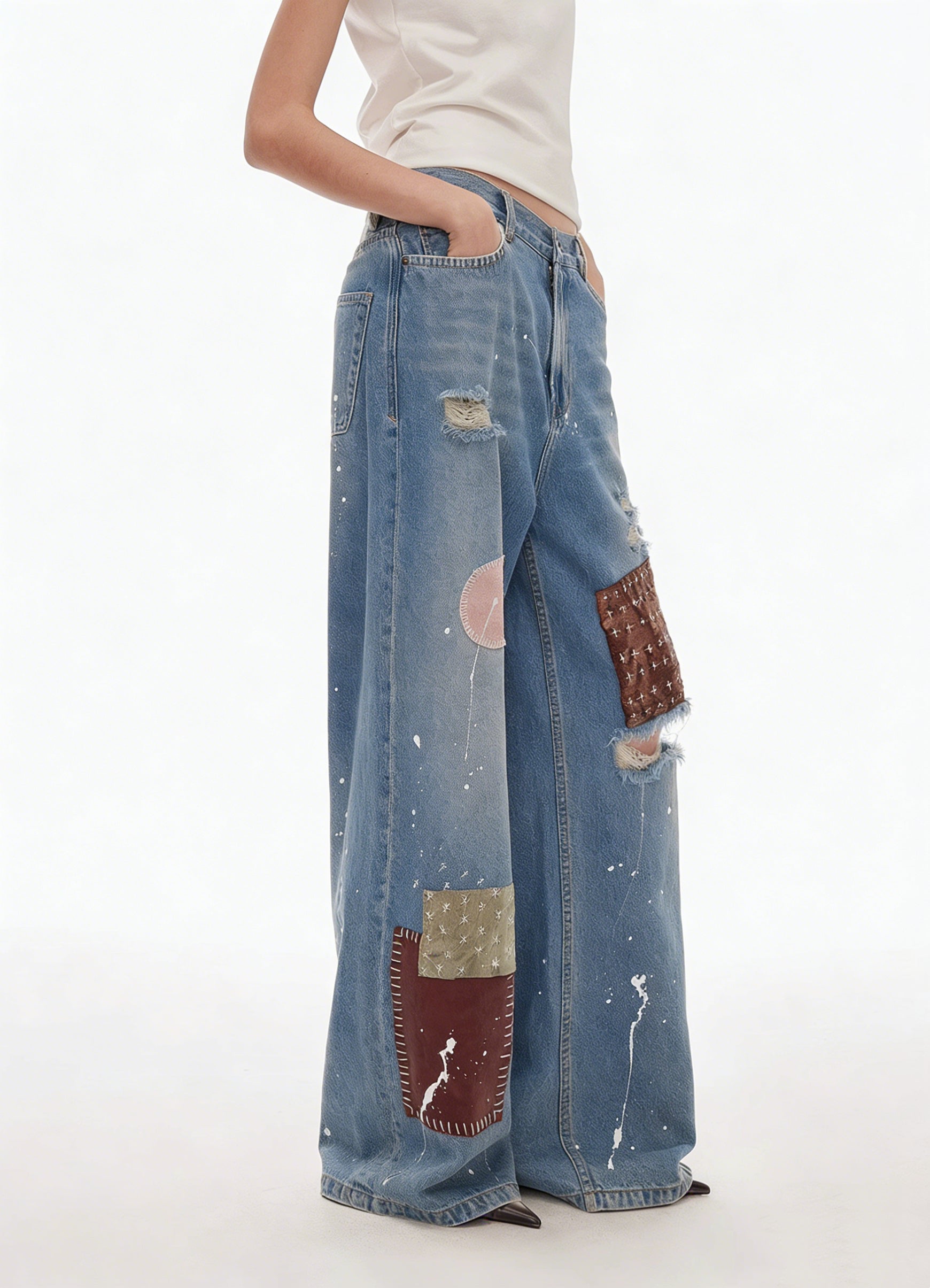 Close-up of patchwork detail on blue distressed wide-leg jeans