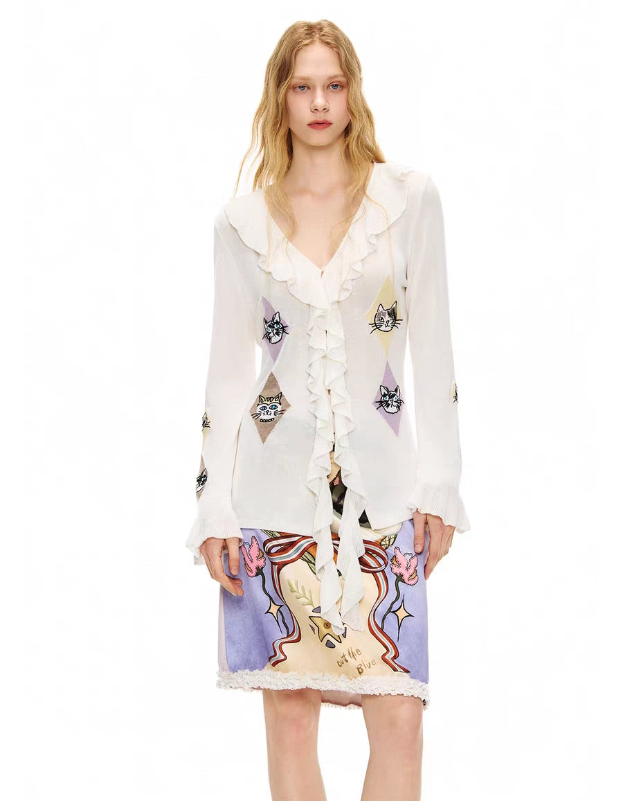 Front view of ivory ruffle tie-front cardigan top with cat argyle motifs, model wearing