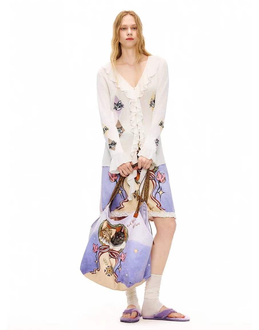 Front view of ivory ruffle tie-front cardigan top with cat argyle motifs, model wearing