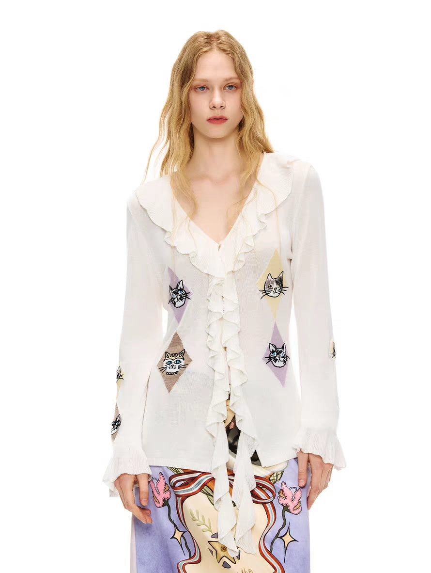 Front view of ivory ruffle tie-front cardigan top with cat argyle motifs