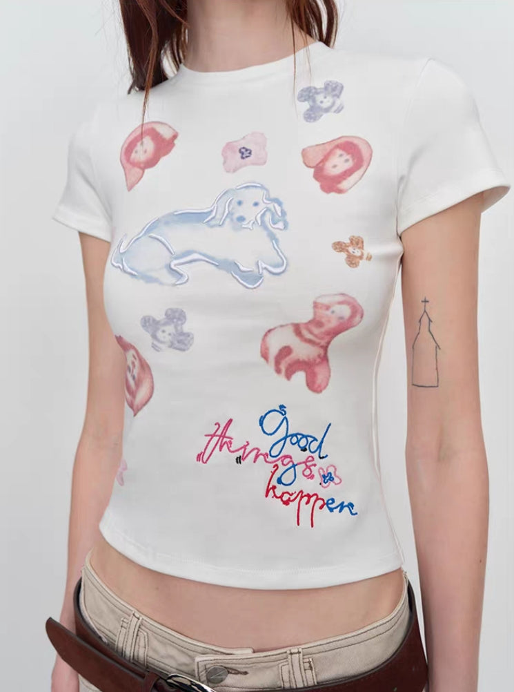 Close-up of puppy graphic and “Good things happen” lettering on white tee