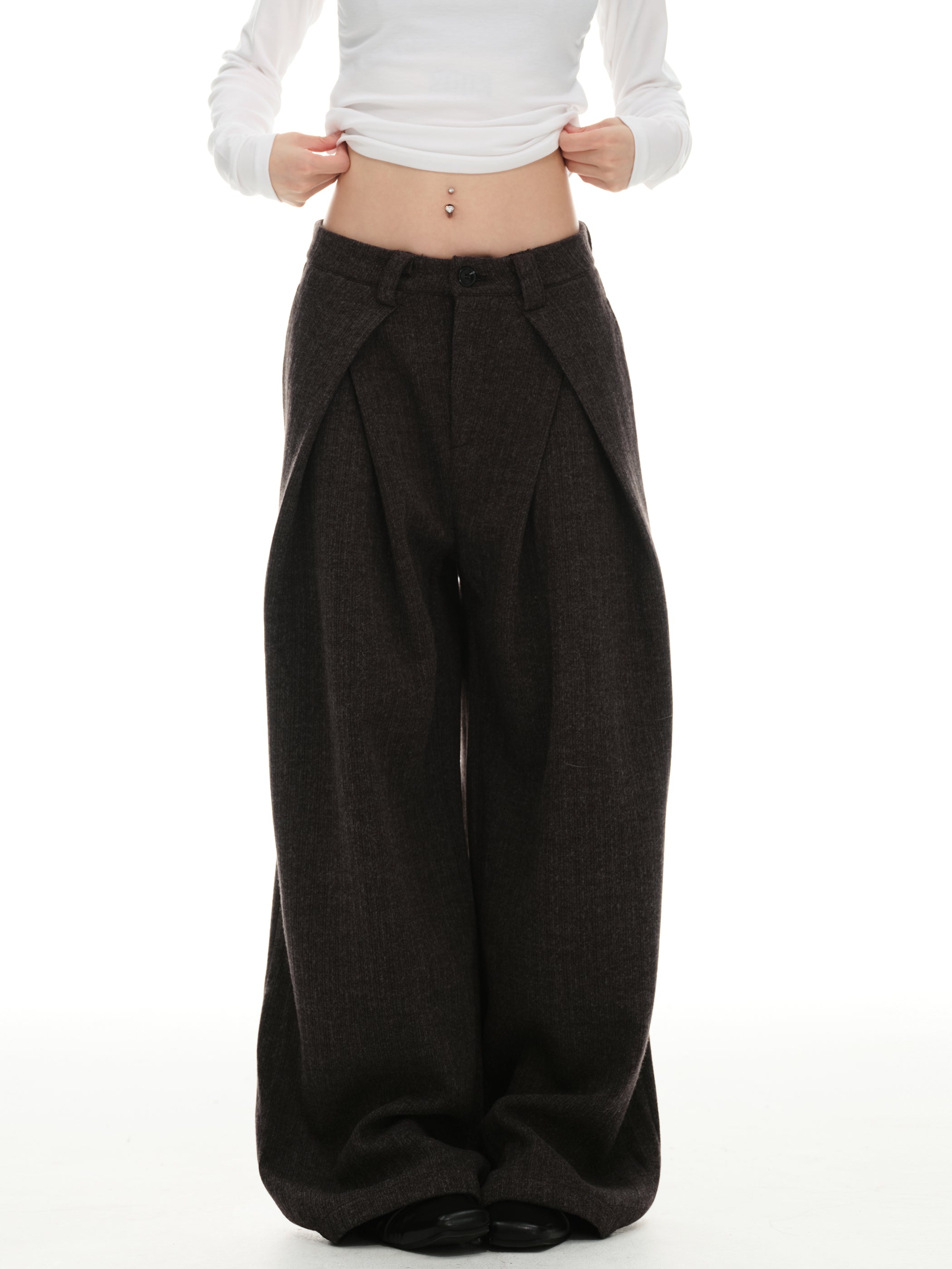 Close-up of dark mocha wide-leg trousers showing mid-rise waist and folded front overlay