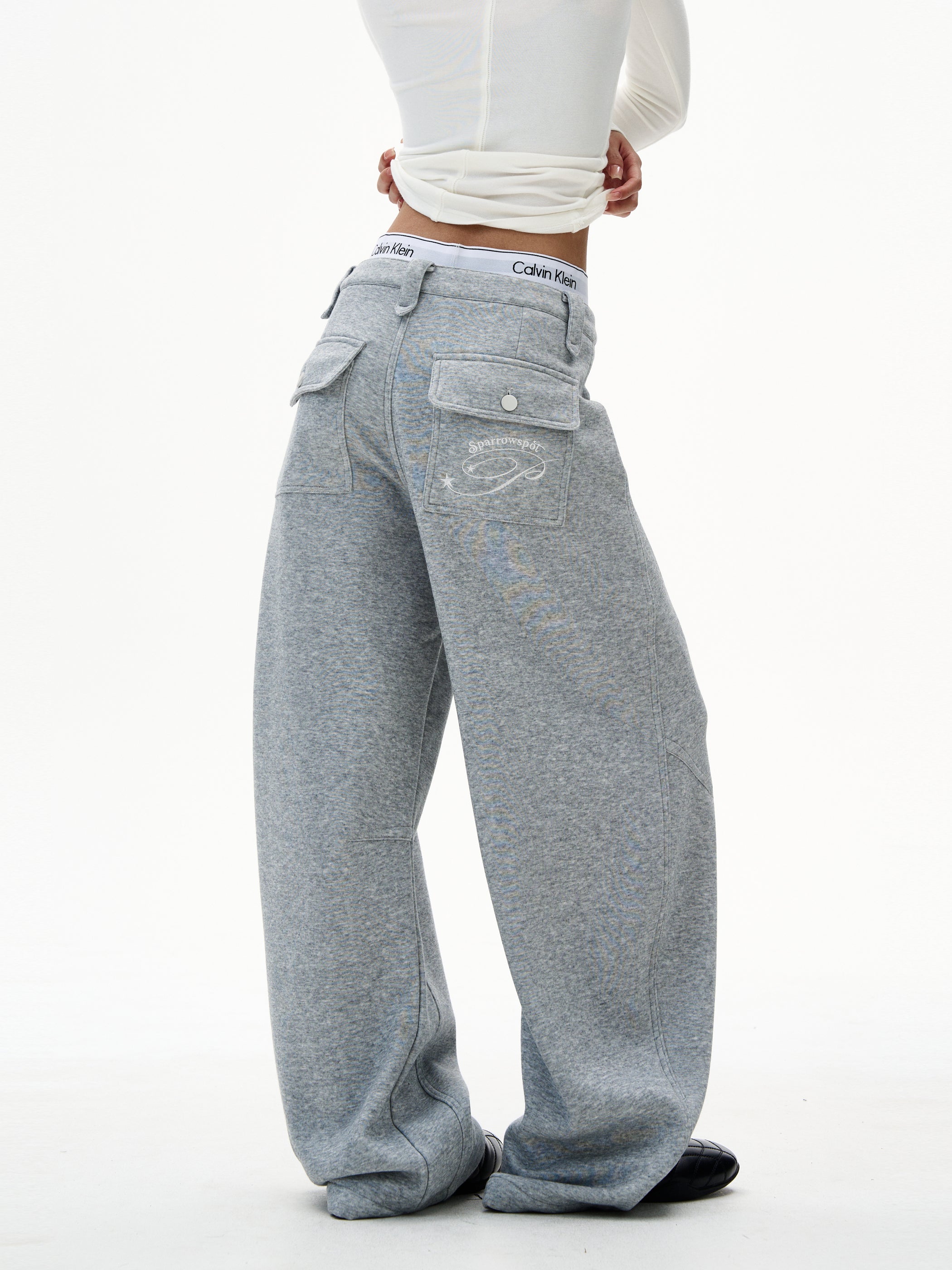 Back view of heather grey wide-leg sweatpants with oversized flap pockets and graphic detail