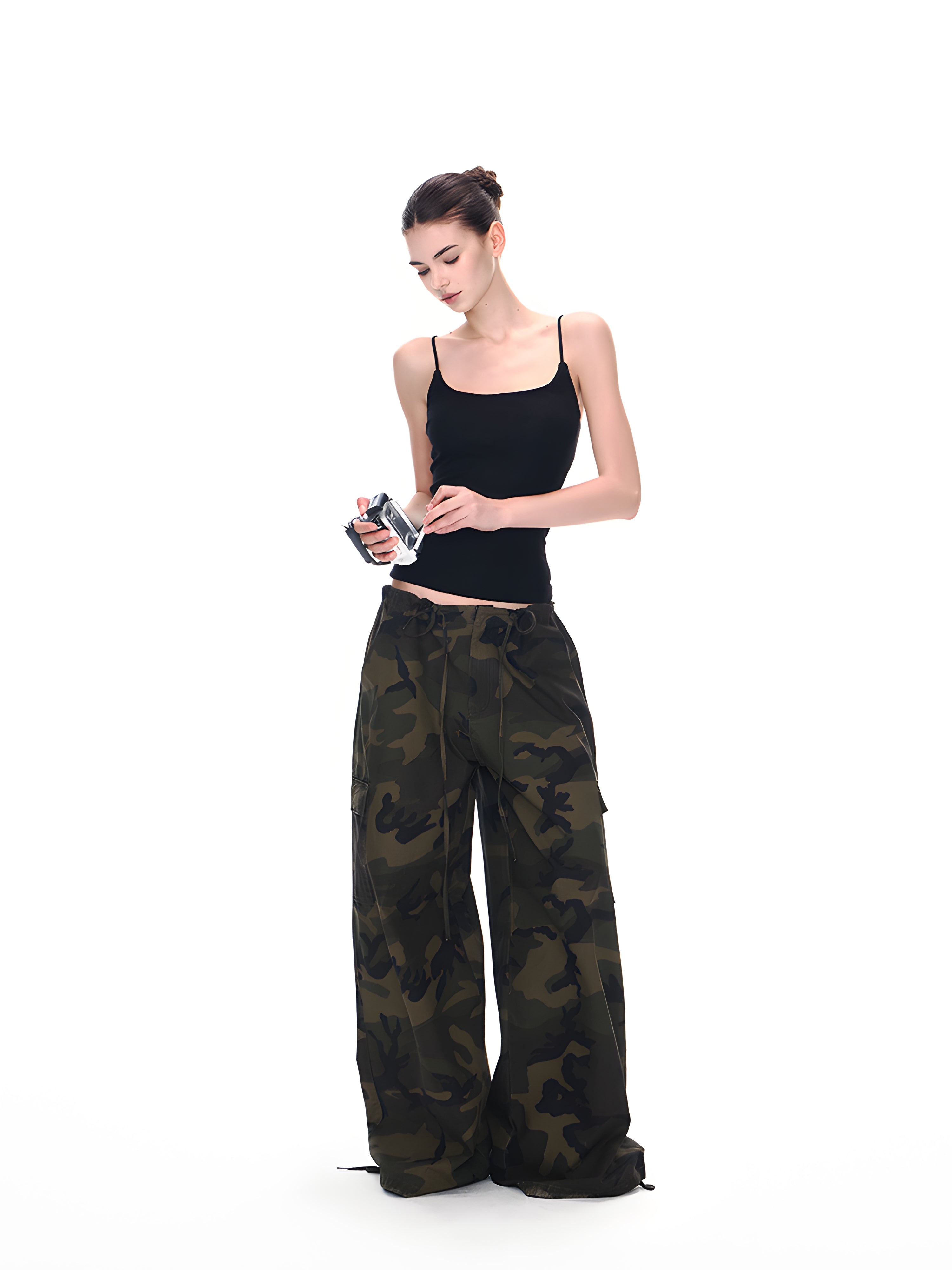 Model wearing low-rise camo cargo pants with black cami, full-body shot