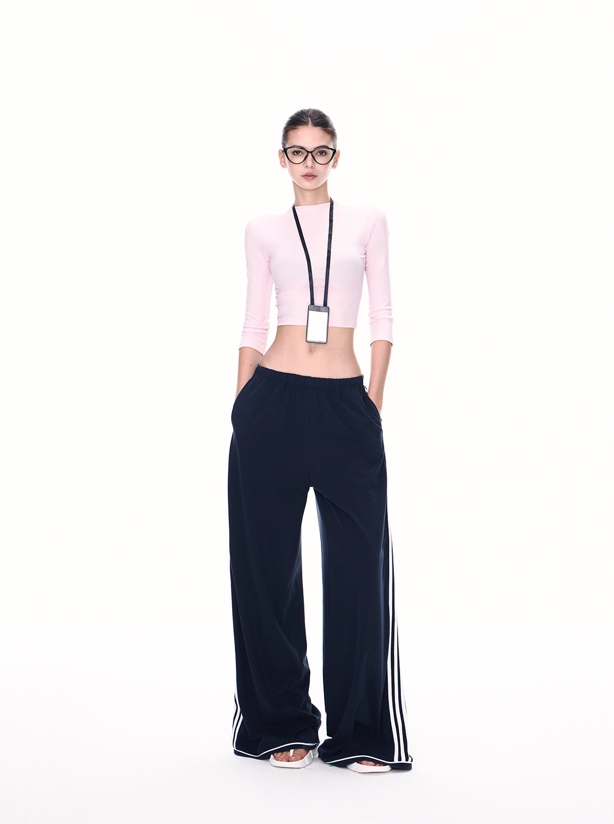 Model wearing deep navy ultra-wide side stripe track pants with pink crop top, full-body front view