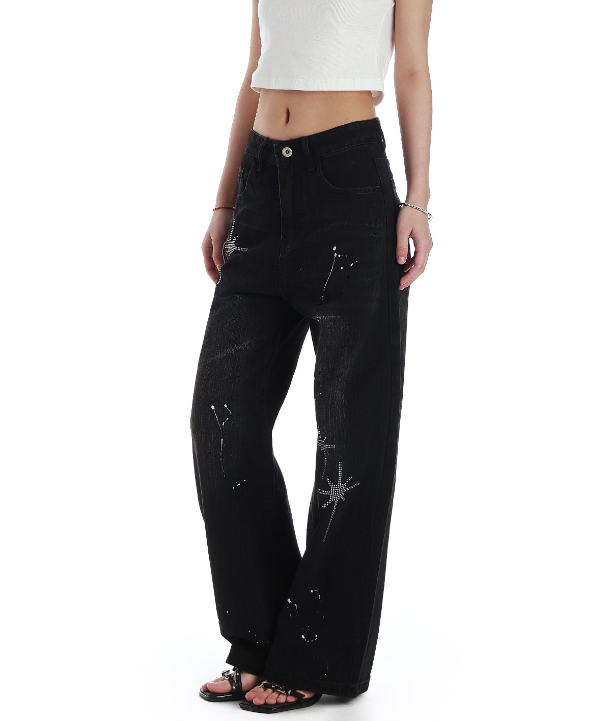 Angled detail view of black rhinestone wide leg jeans showing the washed denim texture and star embellishments