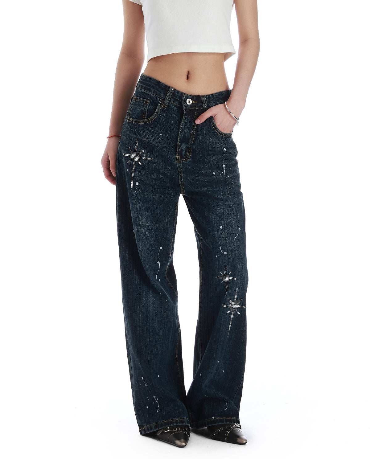 Close-up front view of black rhinestone wide leg jeans showing the high waist, pocket details, and silver star embellishments