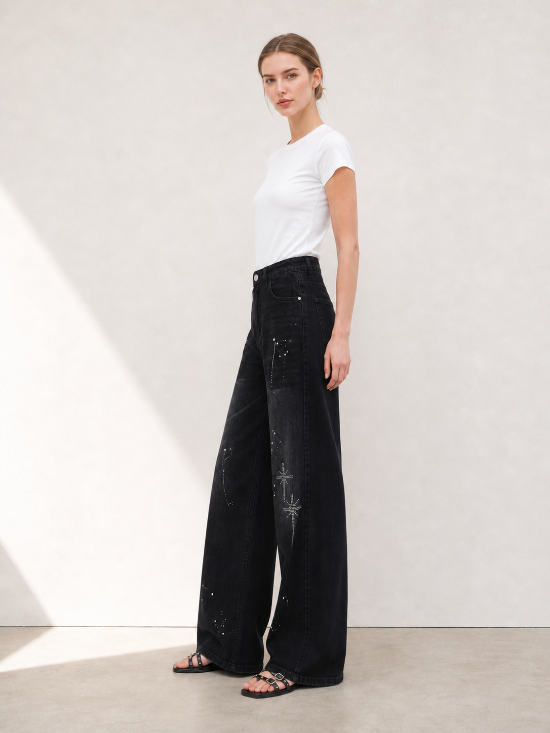 Side view of black rhinestone wide leg jeans showing the loose straight wide leg silhouette