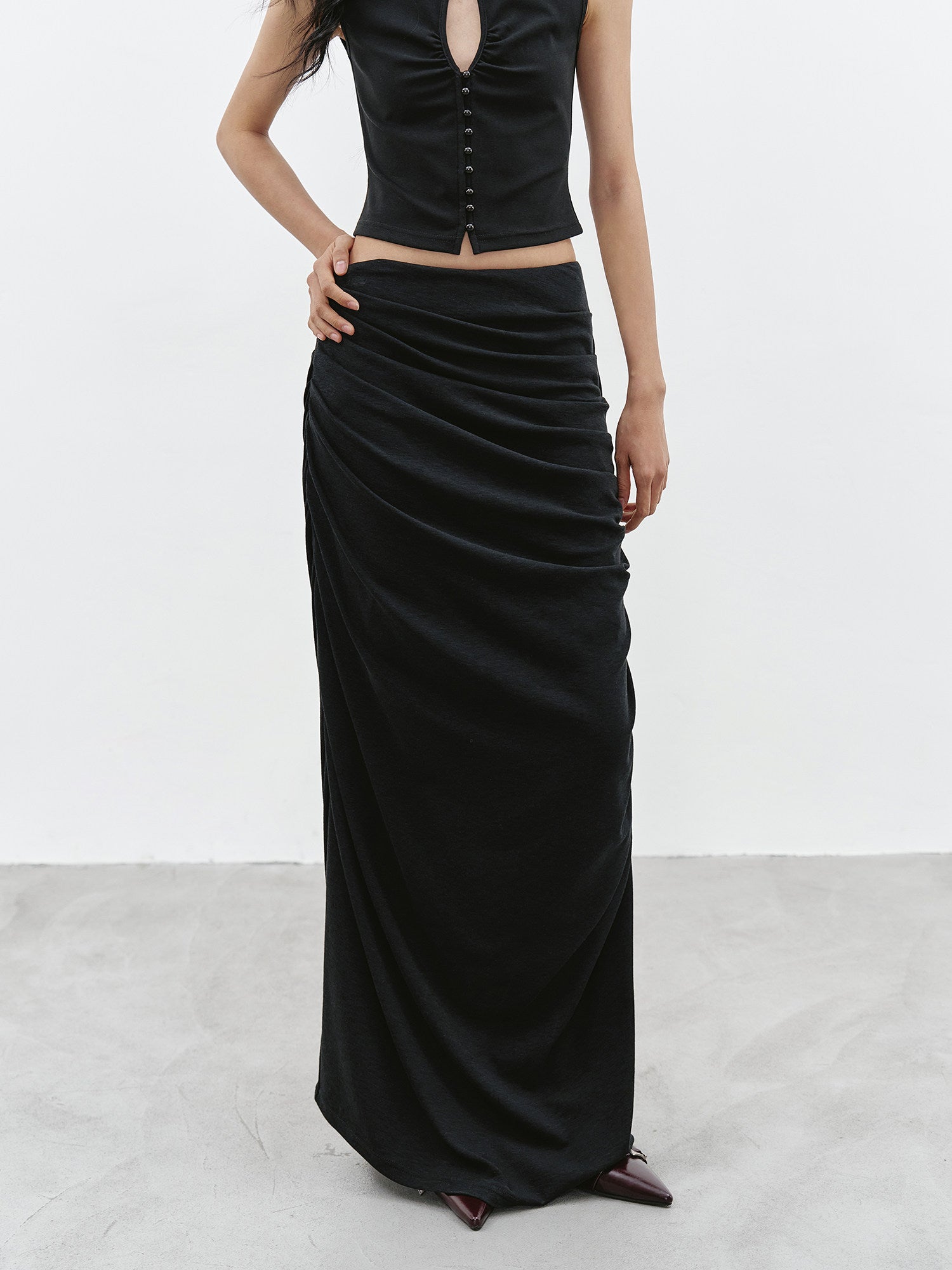 Black ruched maxi skirt front view with draped side detail