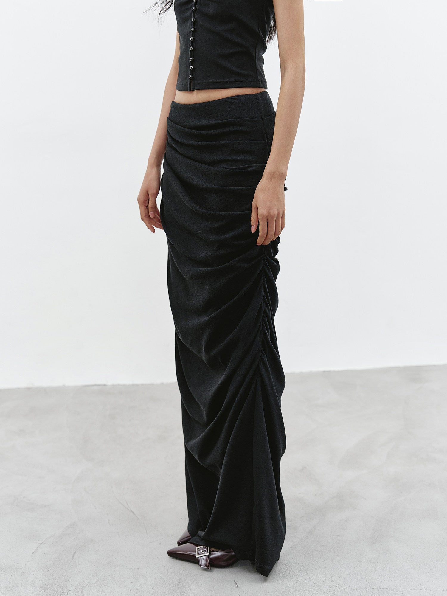 Full body side view of black ruched maxi skirt