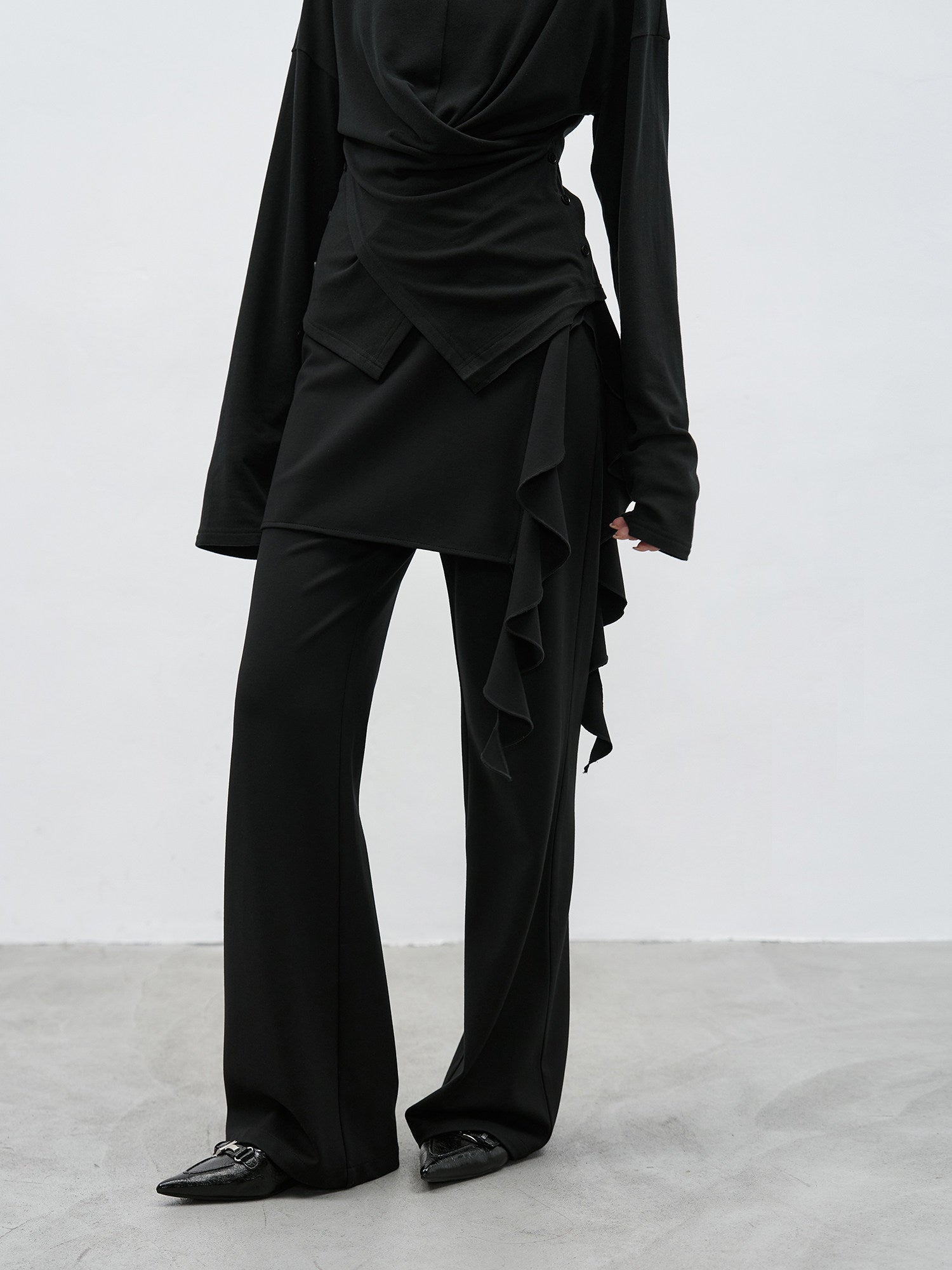 Full body side view of black ruffle layered high waist flared pants