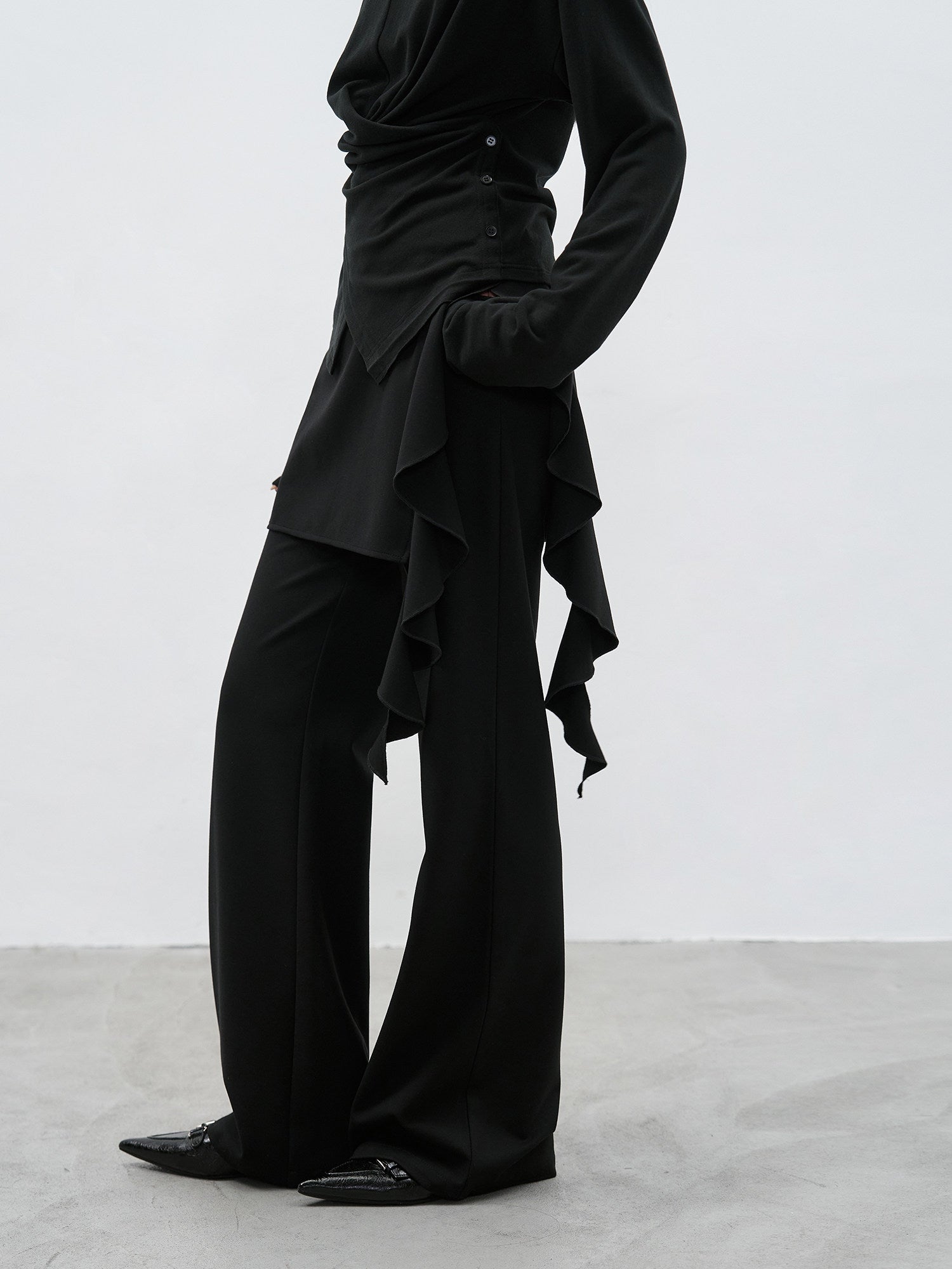 Profile view of black ruffle layered high waist flared pants with layered side detail