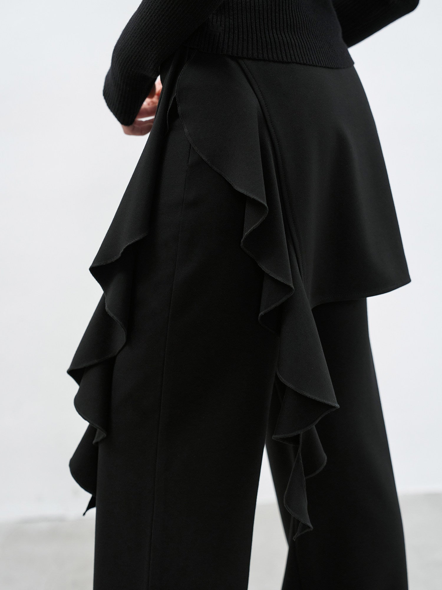 Side detail of black ruffle layered high waist flared pants