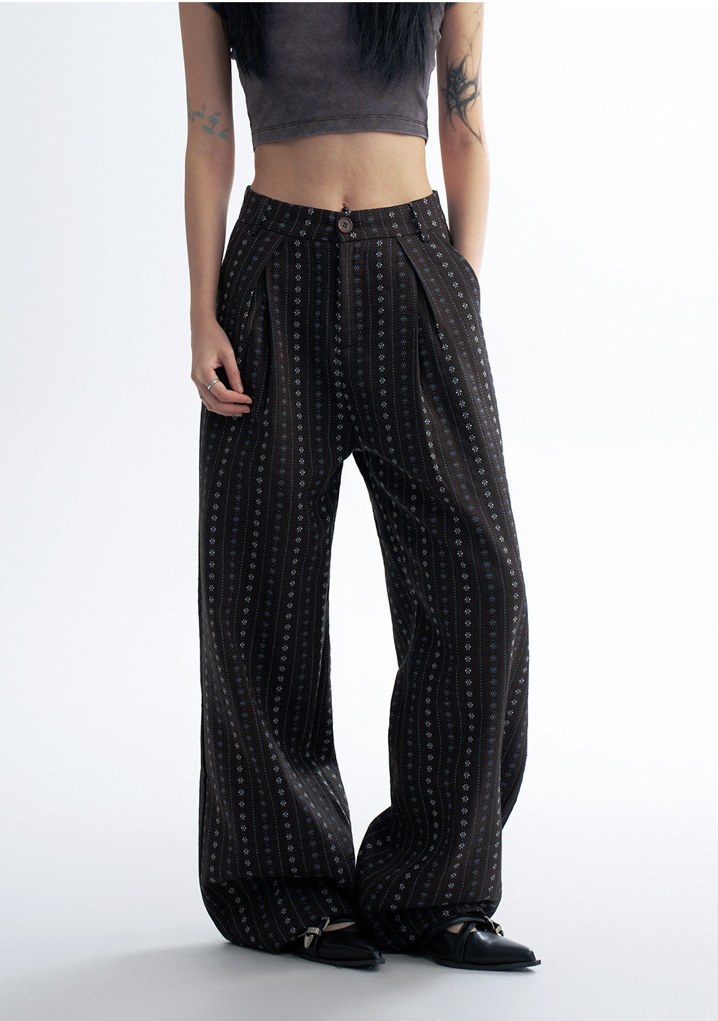 Close-up front detail of black striped wide leg pants showing the pleated waist, button closure, and vertical dot stripe pattern