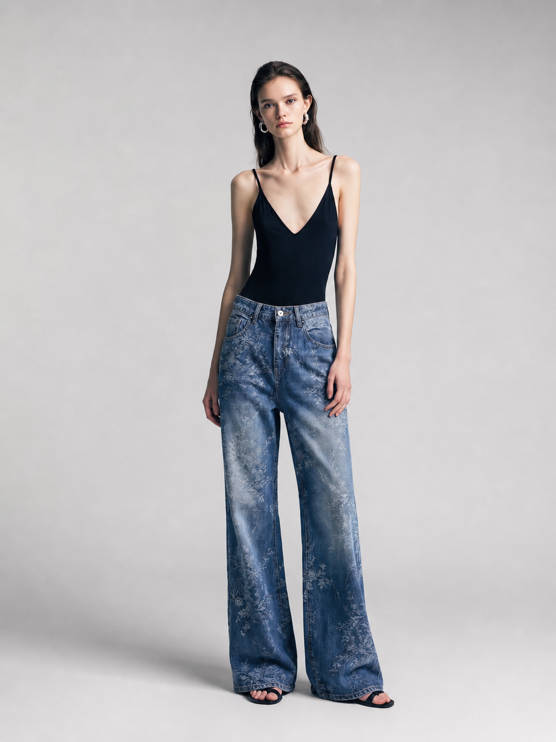 Model wearing blue jacquard wide-leg jeans with a black sleeveless top, front view.