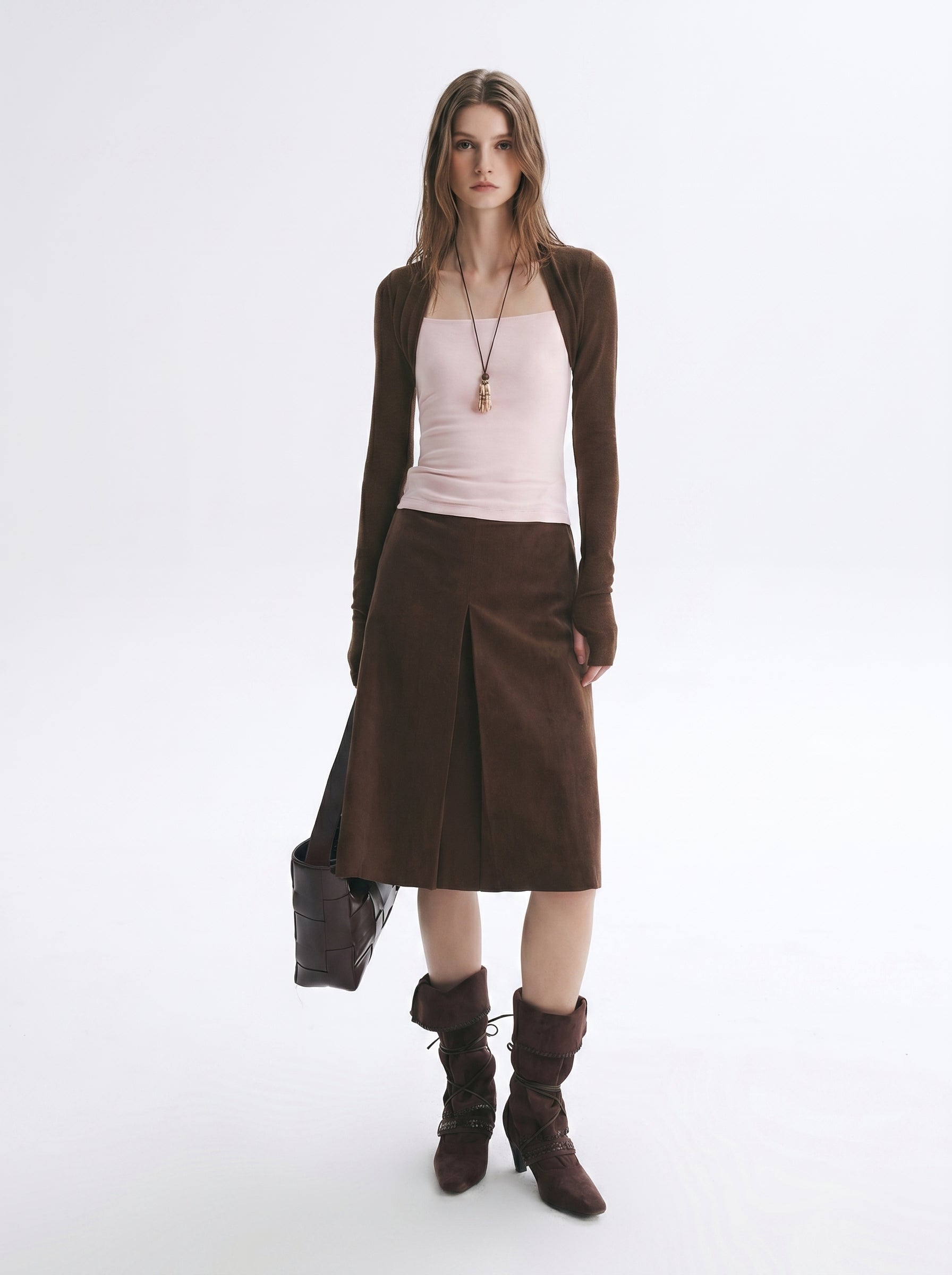Model wearing a brown layered long sleeve top and matching midi skirt set in a minimal studio setting