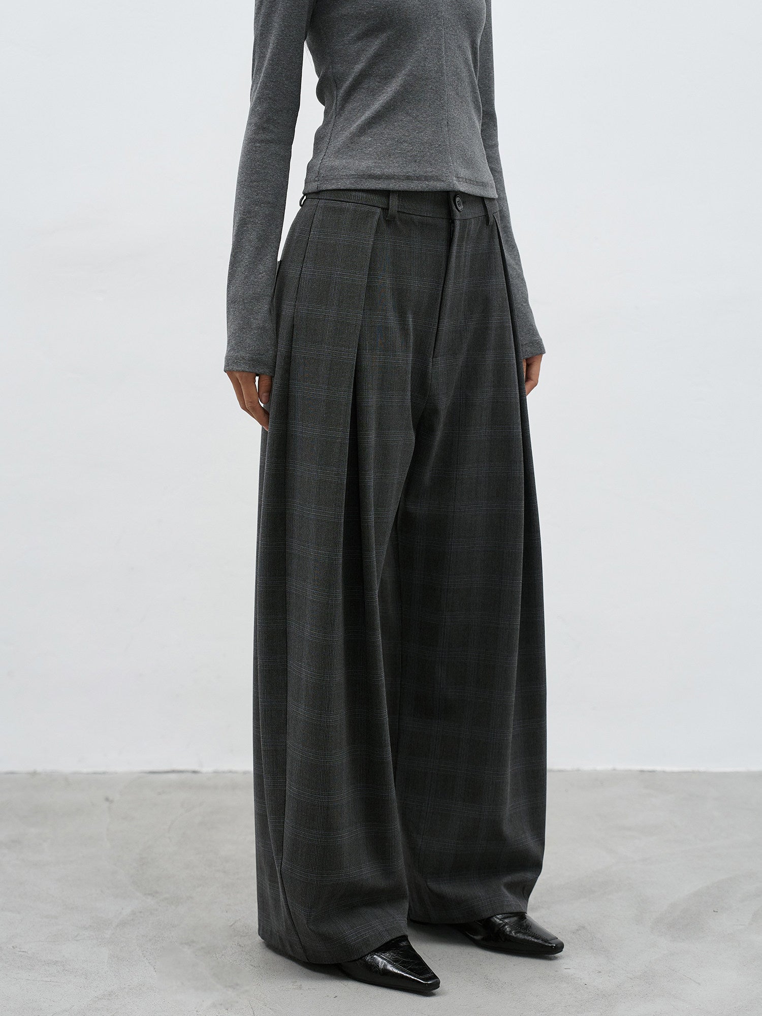 Front detail of charcoal plaid wide leg pants with relaxed drape