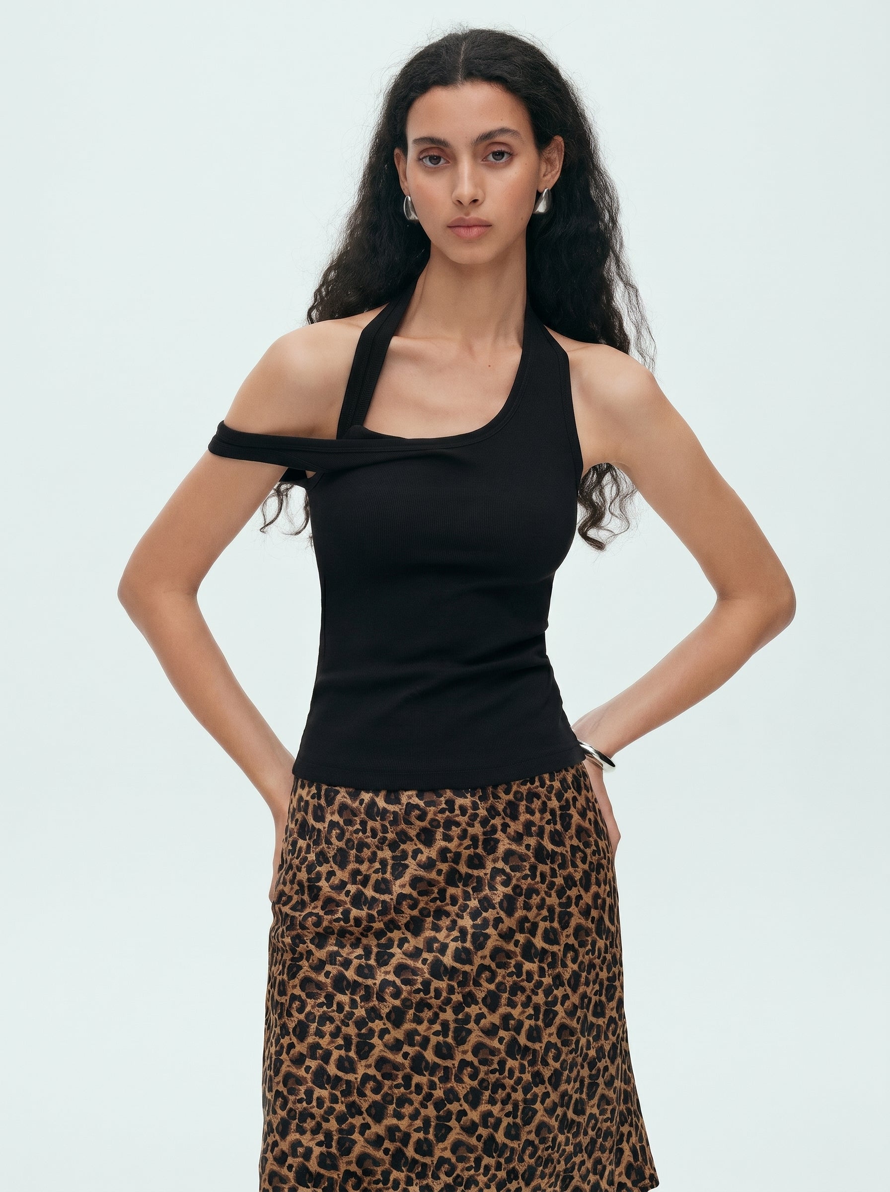 Model wearing a black convertible halter off shoulder top with a brown leopard print skirt