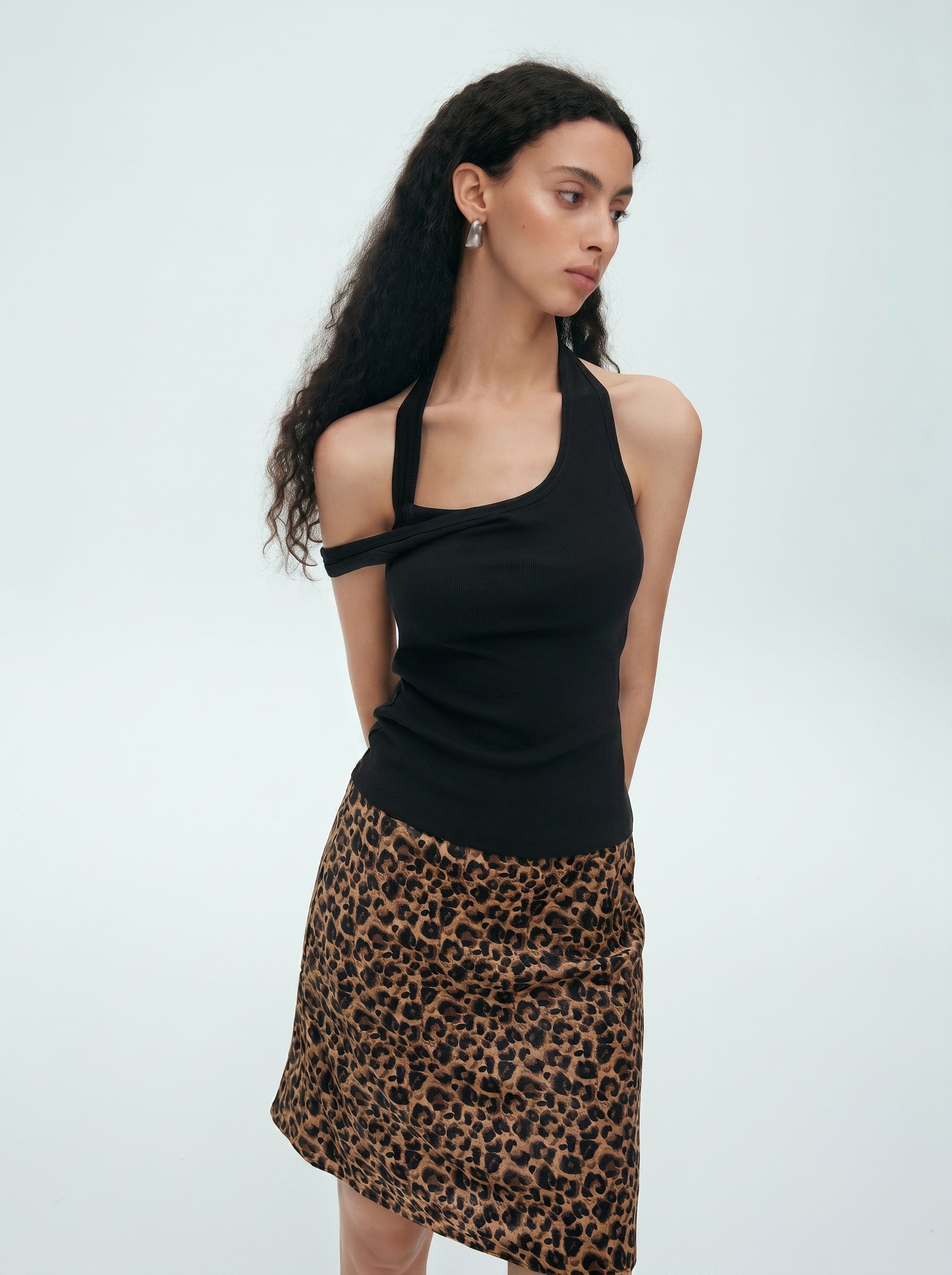 Side view of black convertible halter off shoulder top styled with a leopard print skirt