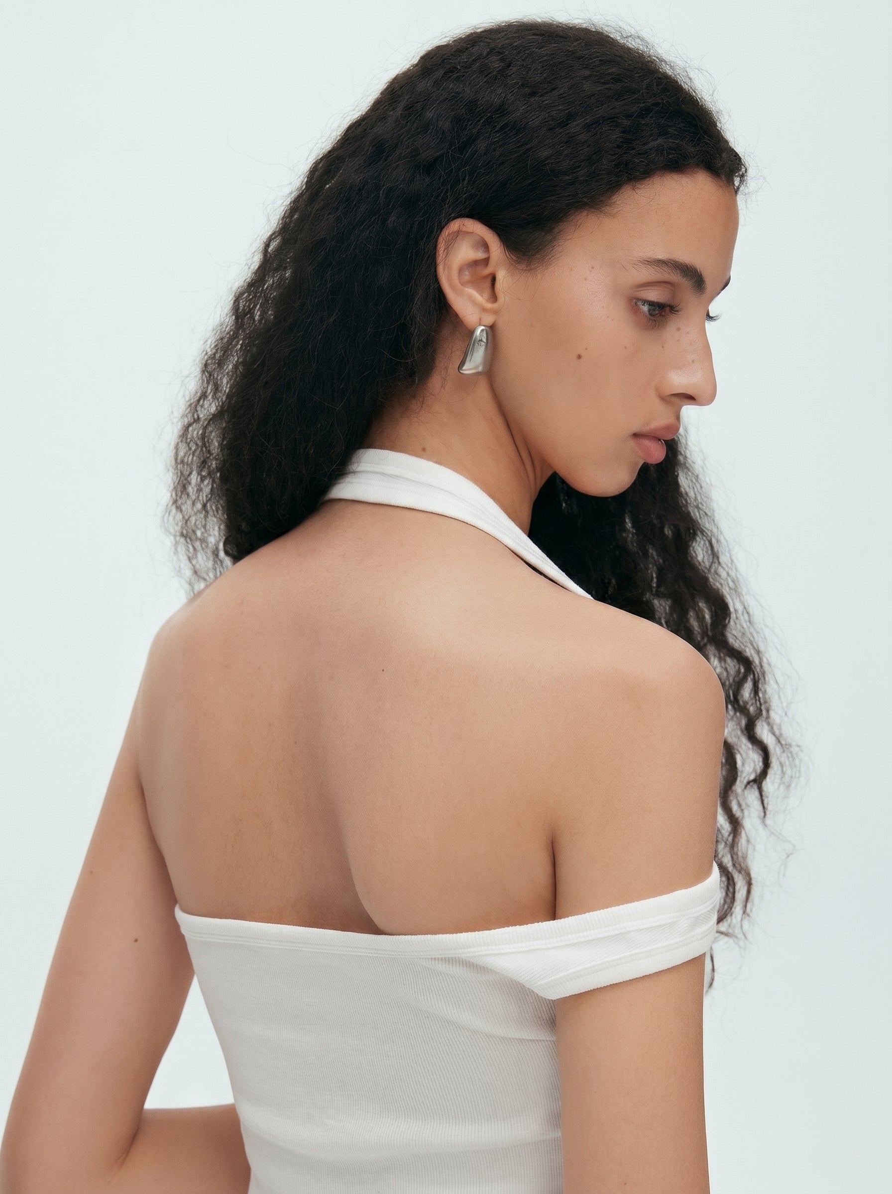 Back detail view of white convertible halter off shoulder top showing the open shoulder and halter neckline