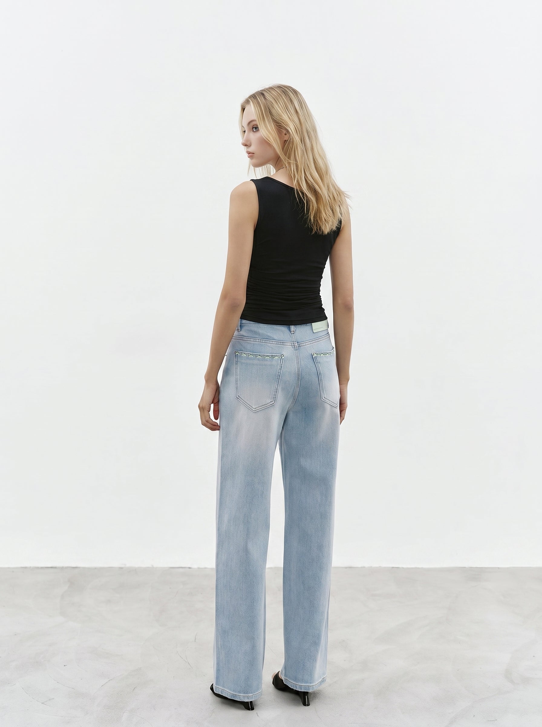 Black cowl neck sleeveless top back view styled with light wash jeans