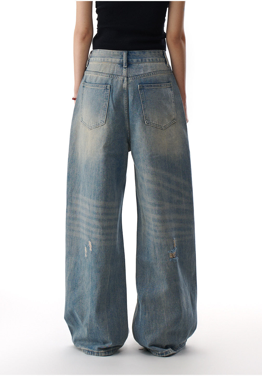 Back detail of distressed blue wide leg jeans showing patch pockets, faded denim wash, and oversized wide leg shape