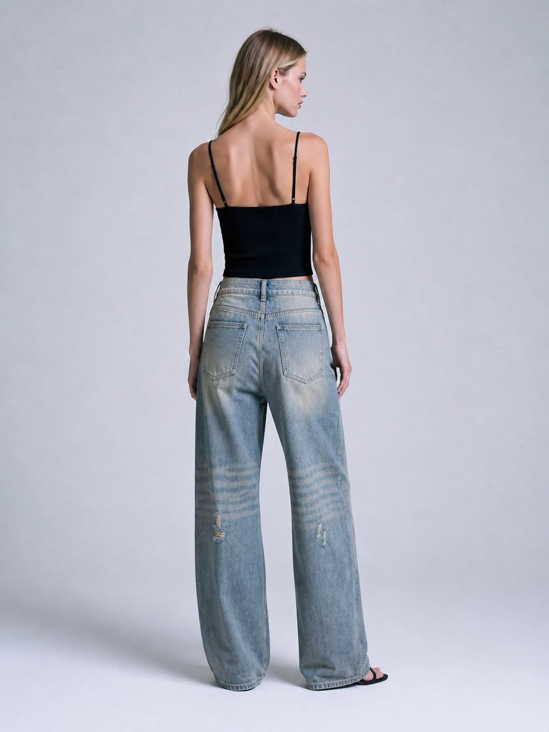 Back view of distressed blue wide leg jeans with patch pockets, wide leg cut, and light blue vintage wash