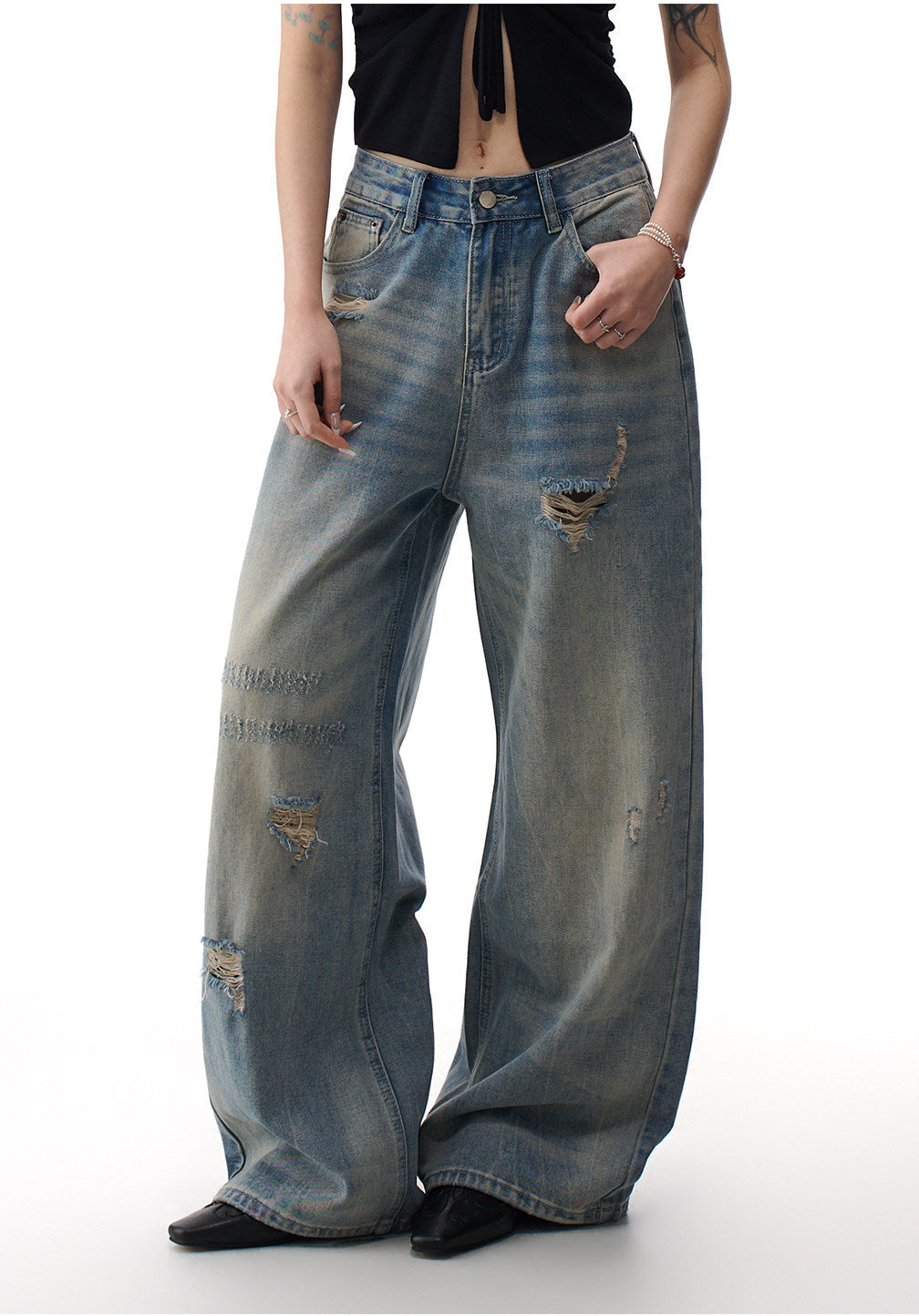 Detail view of distressed blue wide leg jeans showing thigh distressing, washed texture, and loose denim drape
