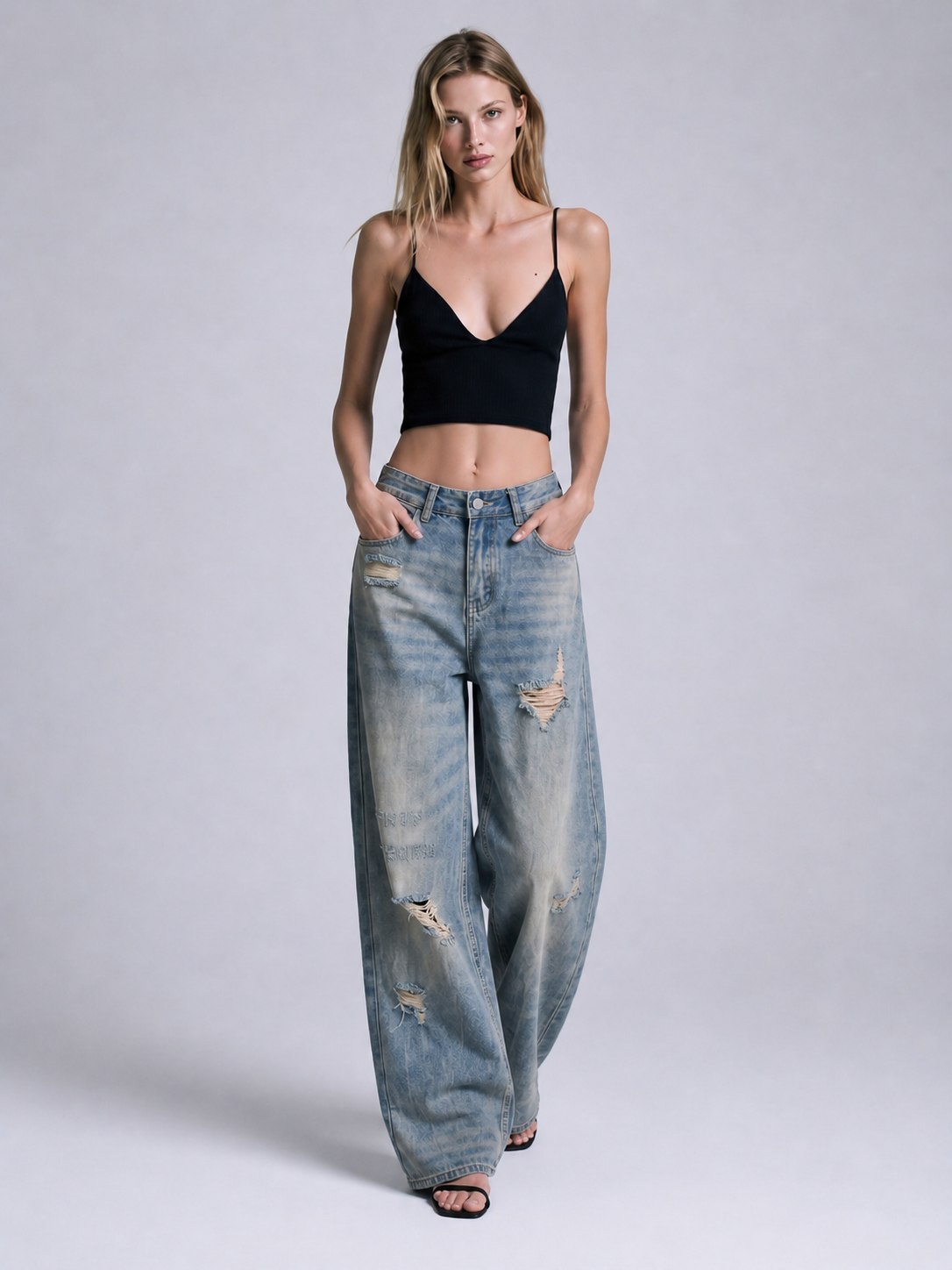 Front view of distressed blue wide leg jeans featuring a washed denim finish, ripped details, and relaxed loose fit