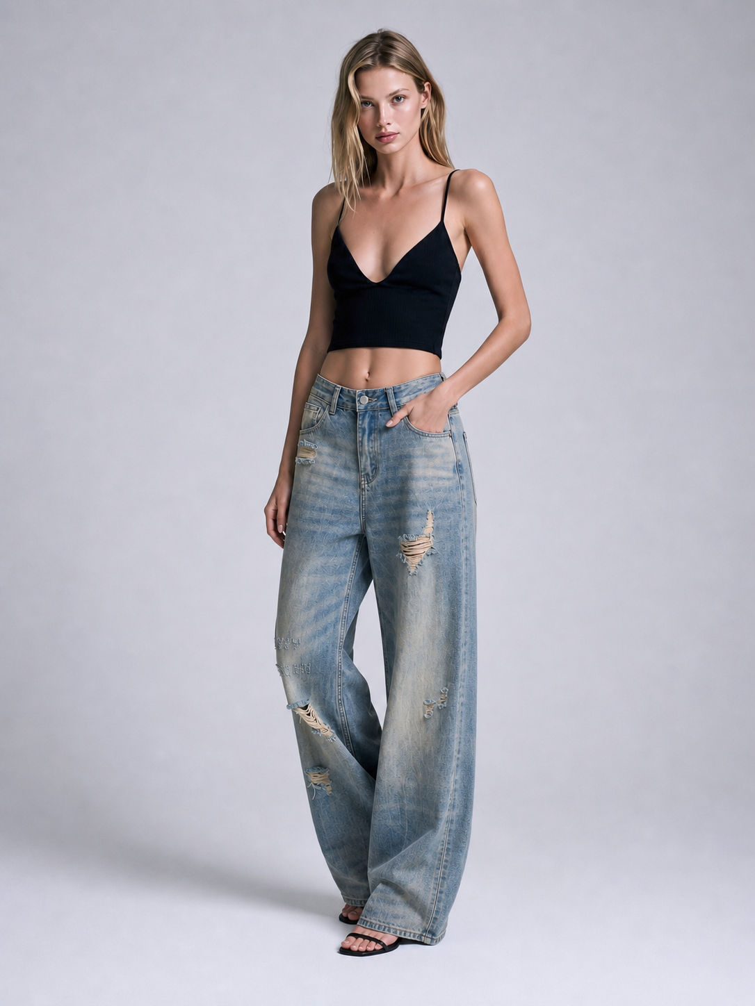 Model wearing distressed blue wide leg jeans with hands in pockets, showing the high waist and wide leg silhouette