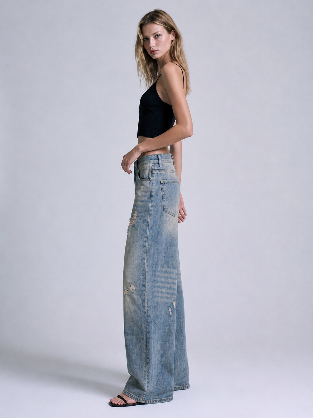 Side view of distressed blue wide leg jeans showing the loose straight wide leg shape and faded wash