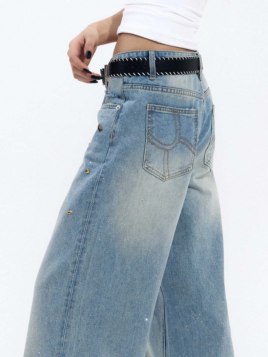 Close-up of light blue jeans waistband, button closure, belt loops, and denim finishing details