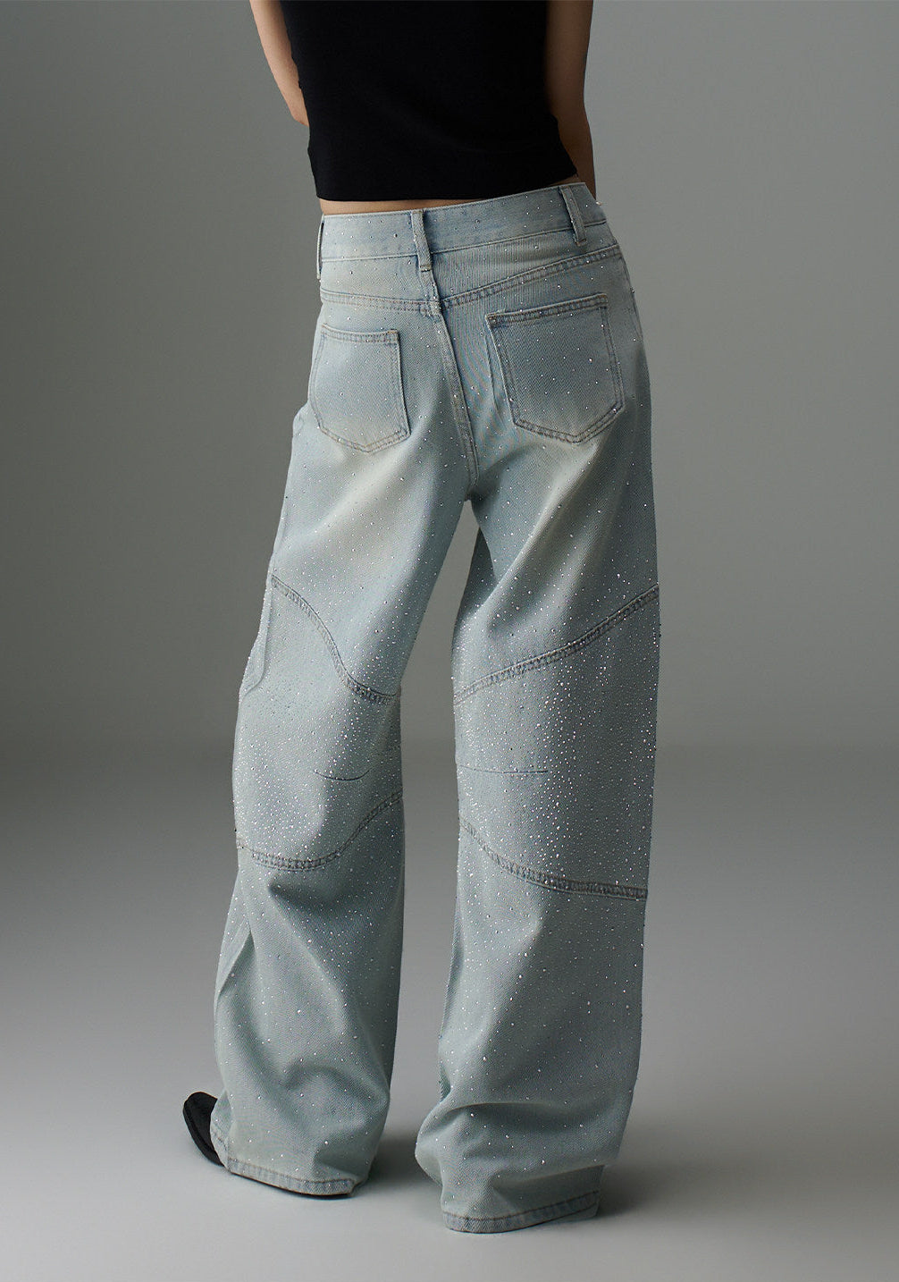 Back view of light wash rhinestone wide leg jeans showing rear pockets, curved seam details, and relaxed wide leg fit