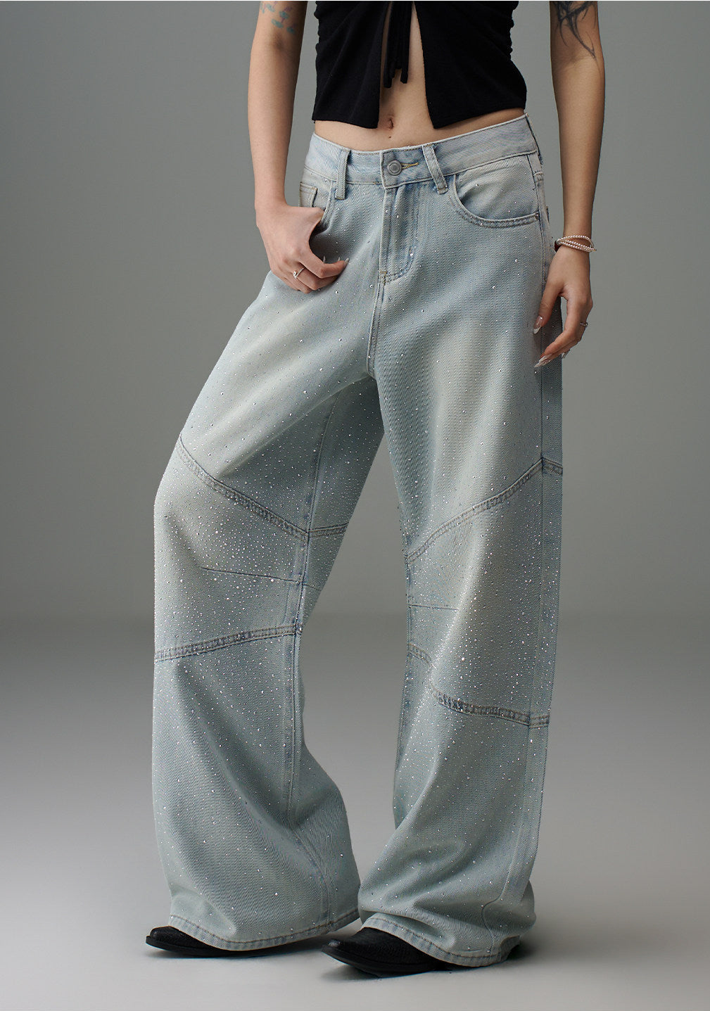 Front angled view of light wash rhinestone wide leg jeans showing the loose drape, panel seams, and rhinestone finish