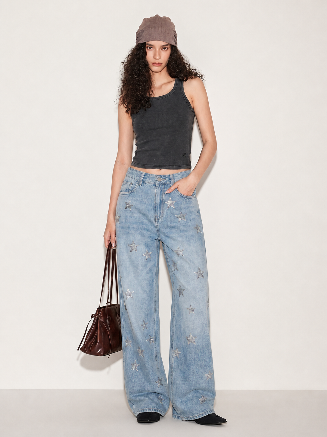 Model wearing light wash wide leg jeans with silver star embellishments, front view