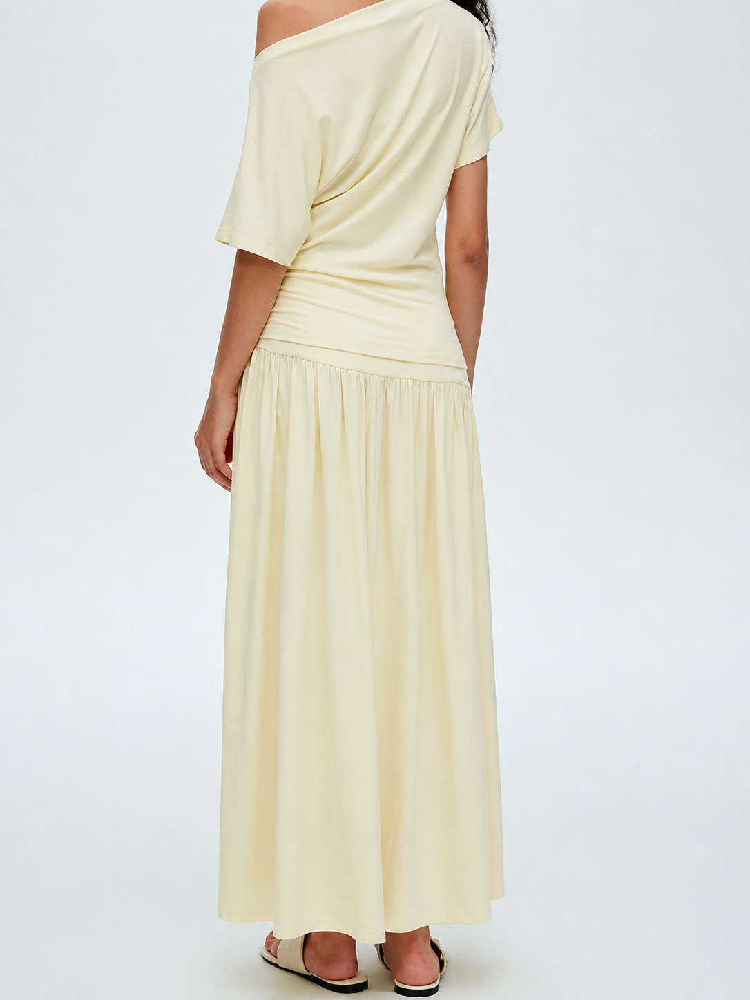 Back view of cream off shoulder draped top and matching maxi skirt set showing the off shoulder neckline and gathered skirt