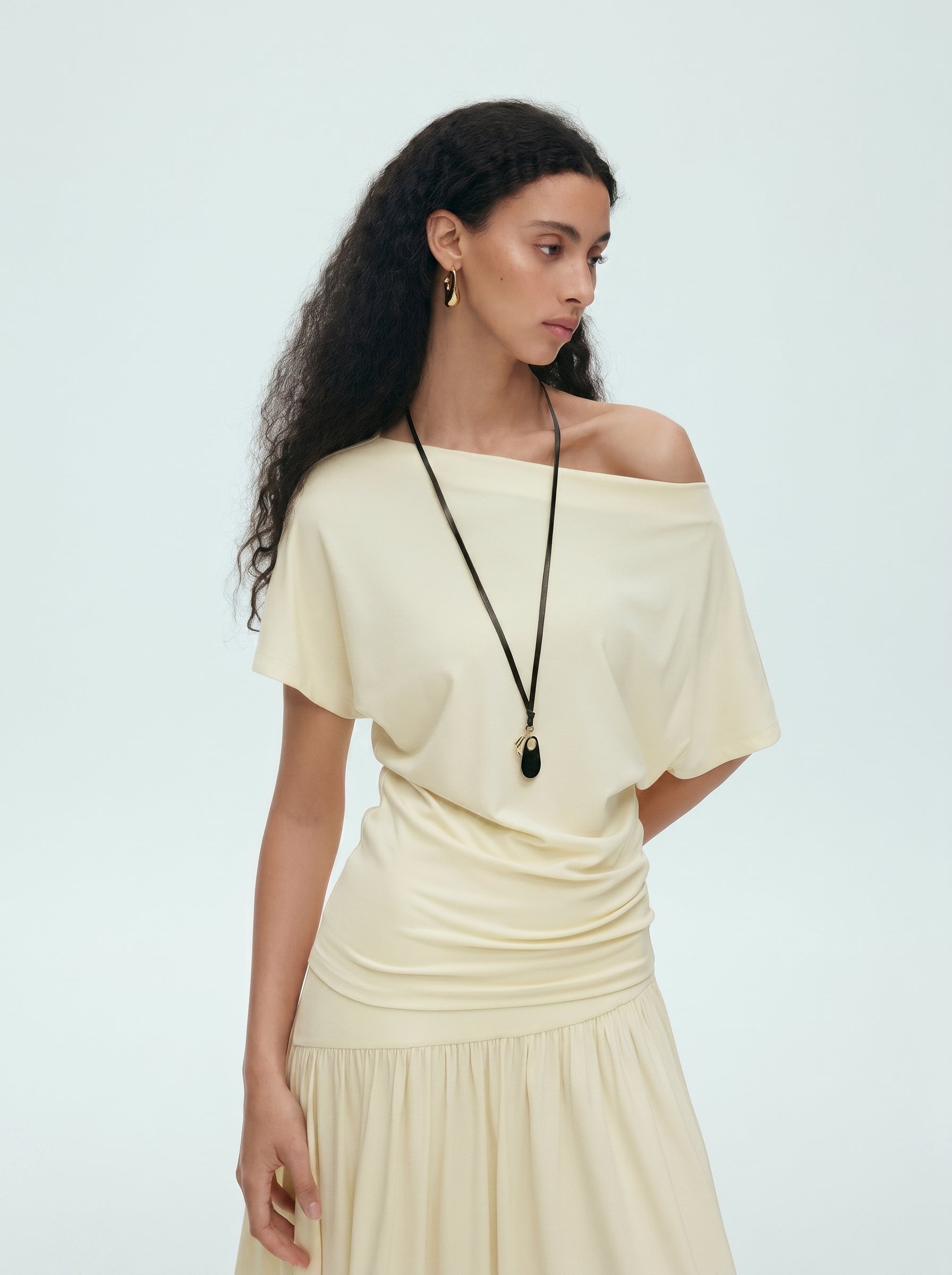 Side view of cream off shoulder draped top and matching maxi skirt set showing the flowing maxi length