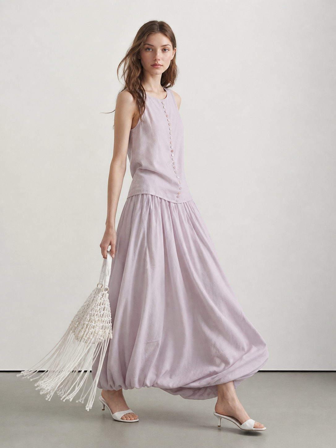 Model wearing a pale blush button-front tank and matching bubble maxi skirt in a soft walking pose