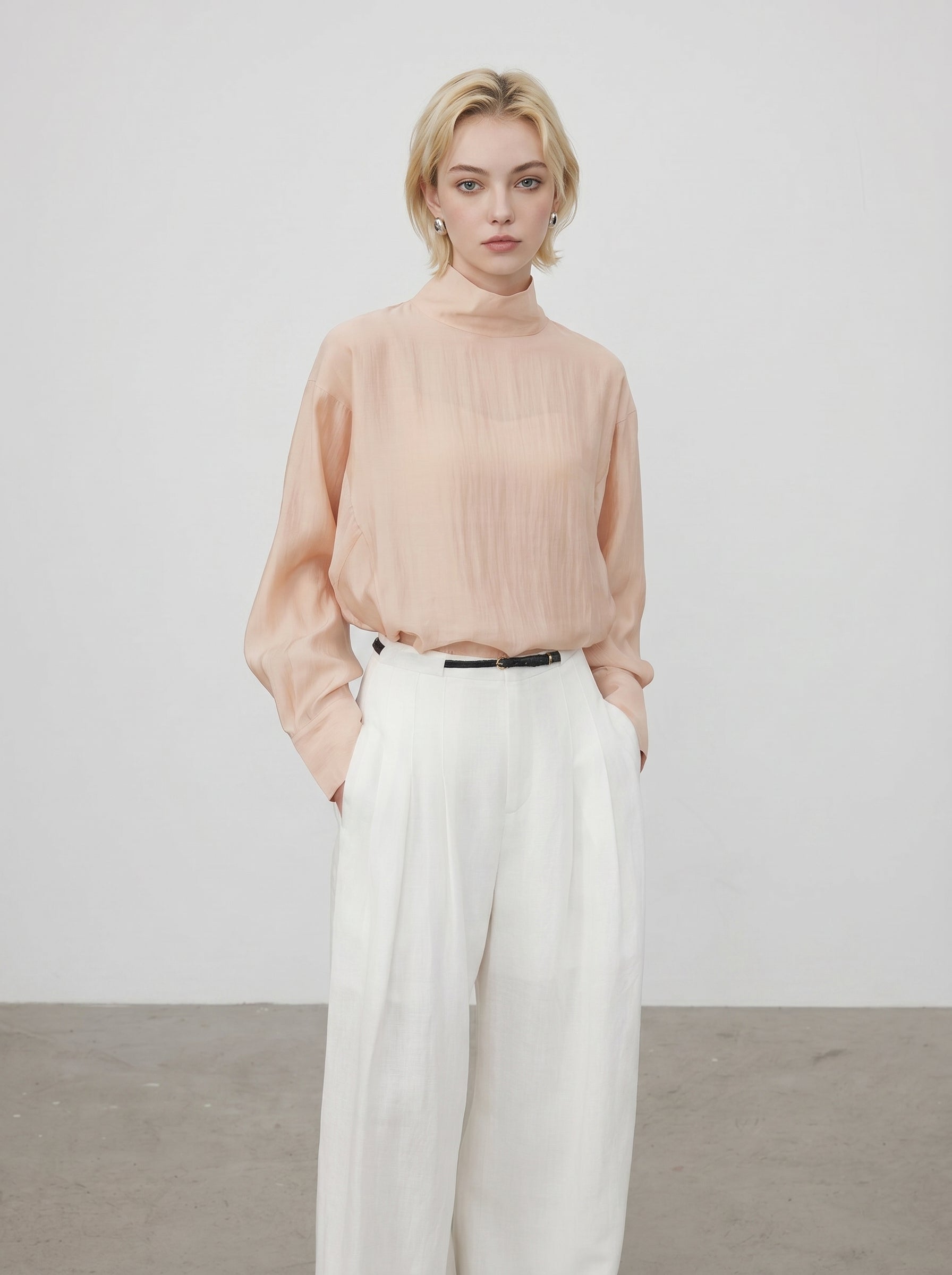 Front view of peach sheer high neck blouse with soft drape and white wide leg pants
