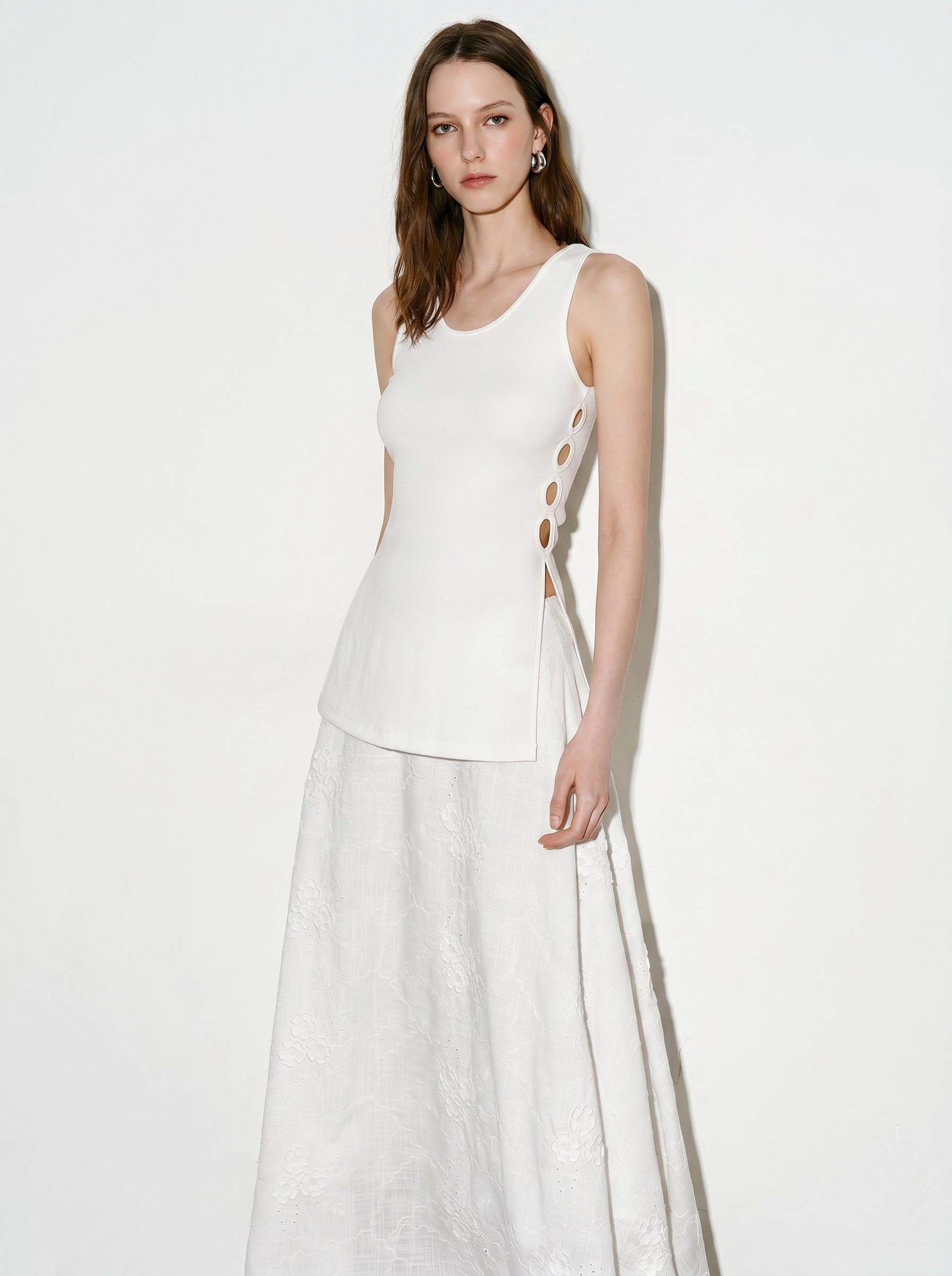 Model wearing a white side ring ribbed tank top with a white maxi skirt in a minimal studio setting